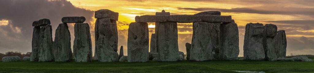 Stonehenge shown with sunset behind a turbulent sky