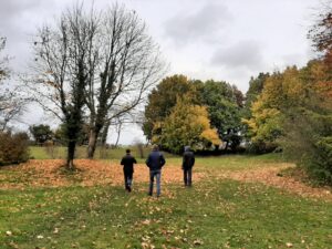 Visit the Cotswolds this November. Picture shows a colourful autumn view with trees dropping leaves and people on a walk.