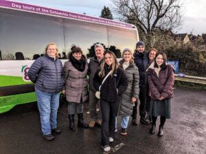 Go Cotswolds tour guests stand outside the branded bus wearing woolly hats and coats