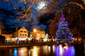 Bourton on the water at night covered with christmas lights looking very twinkly and festive on a Go Cotswolds tour.