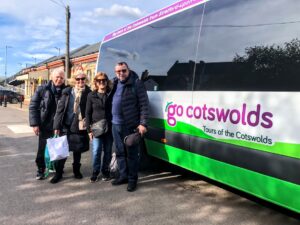 Guests outside a Go Cotswolds tour bus in April in the sun